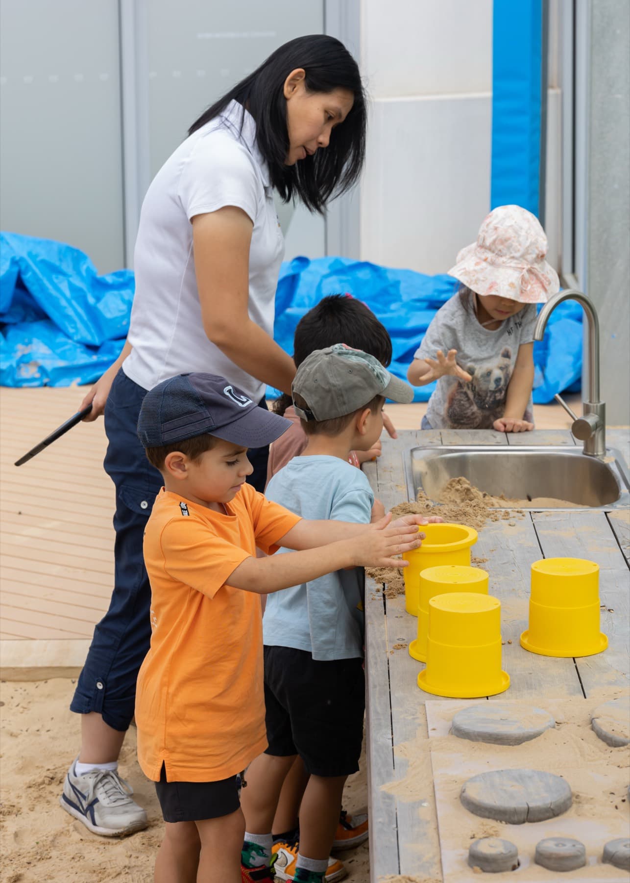 An educator with children at an outdoor play table