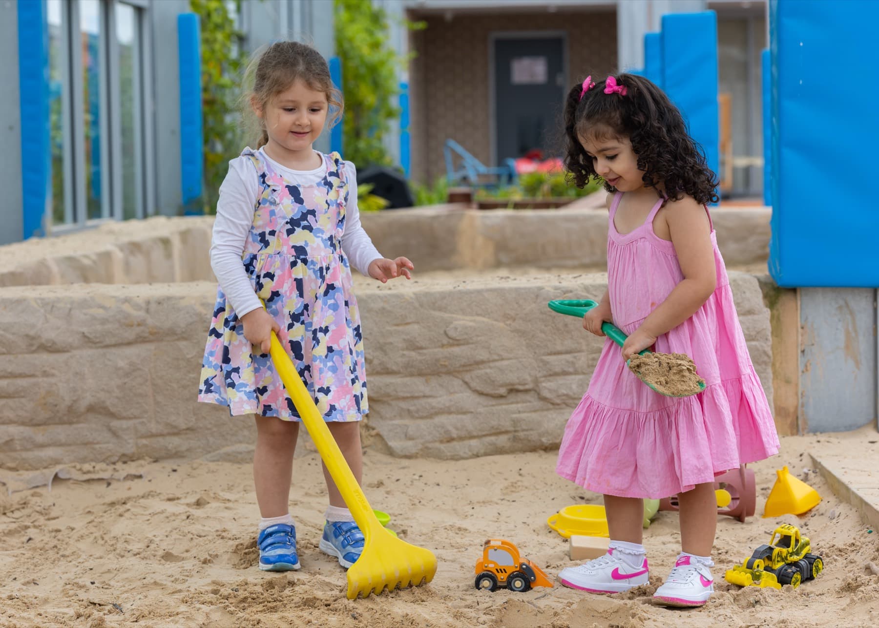 Two children raking the sand pit
