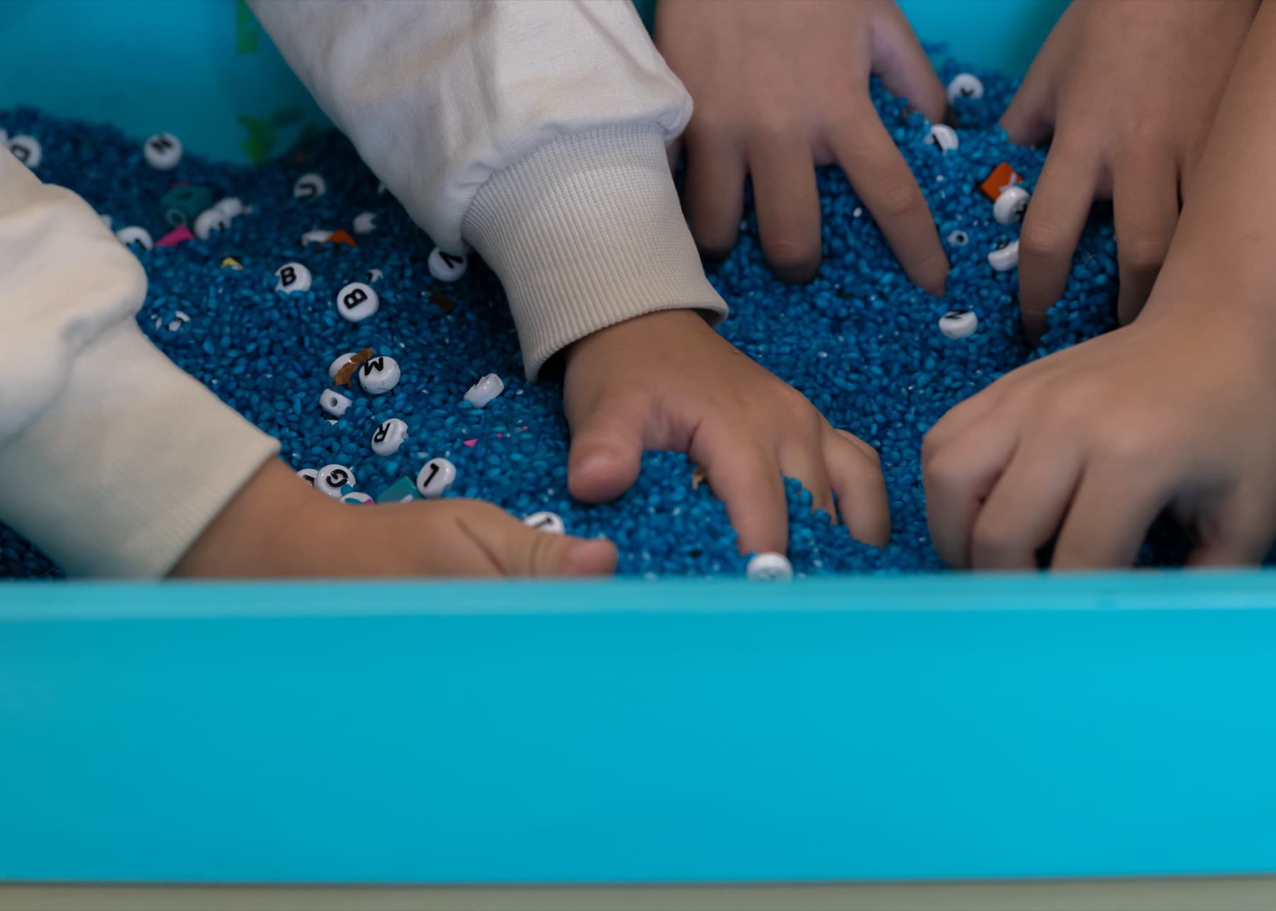 Small hands exploring a tray of sensory play